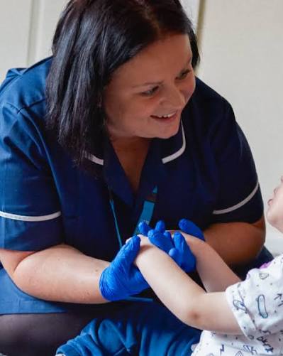 Smiling nurse in uniform holding a young patient's hands
