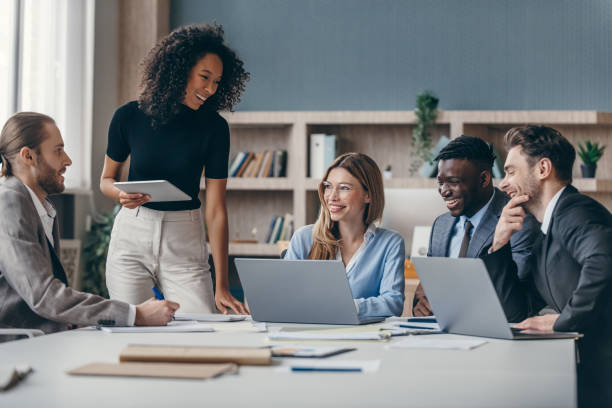 Team of colleagues smiling around laptops in a modern office